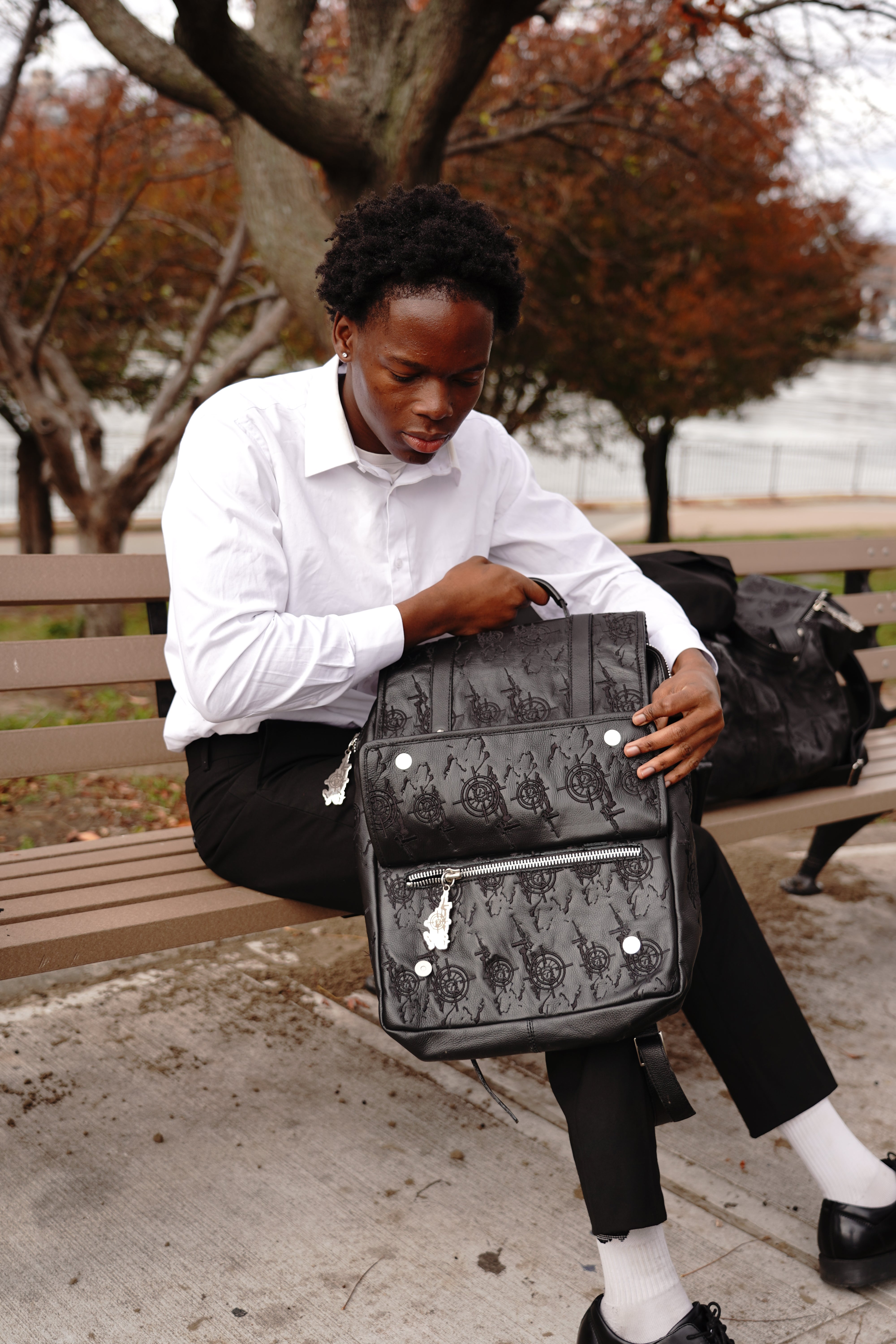 Maison enamy owner sitting down holding luxury backpack