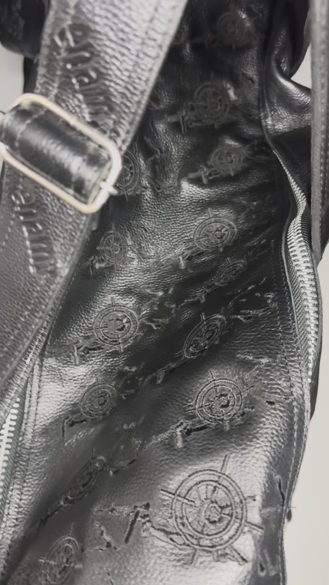 Detail video of black genuine leather duffle bag 
showing embossed Veil For Liberty monogram pattern 
and Enamy charm hardware. Maison Enamy NYC. 21x14.